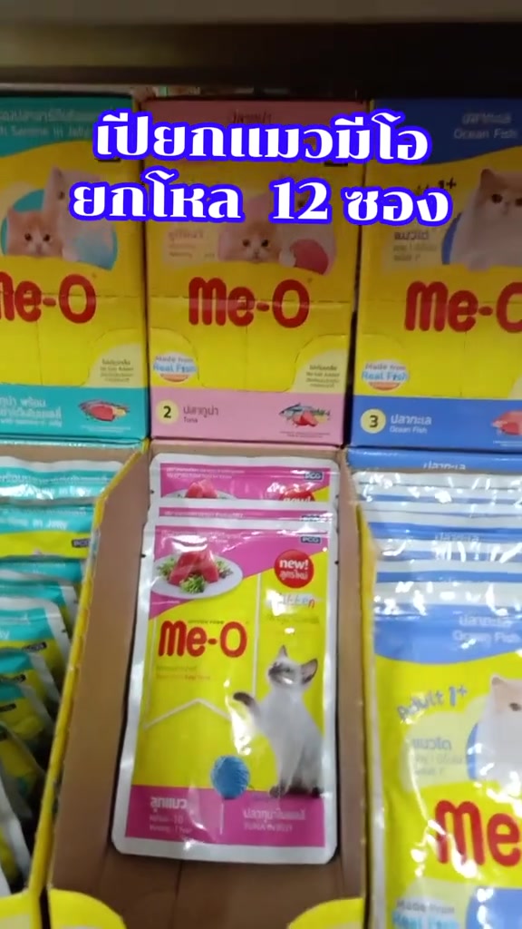โหลอาหารเปียกแมว Me-O แบบซองที่ถูกเปิดแล้ว เห็นซองสีชมพูเรียงอยู่ในกล่อง
