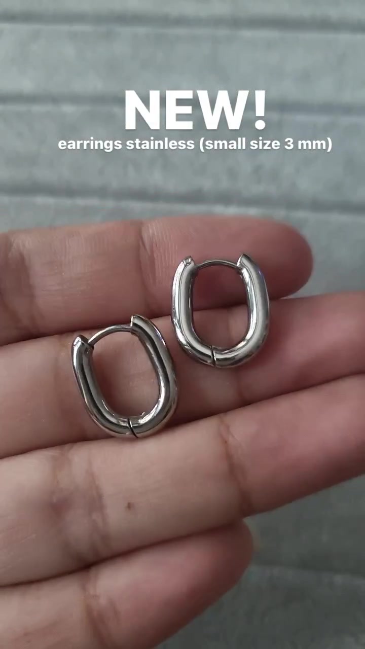 ต่างหูห่วงทรงรีผิวเงาสองวงวางบนฝ่ามือ เห็นความเงางามของเนื้อโลหะชัด