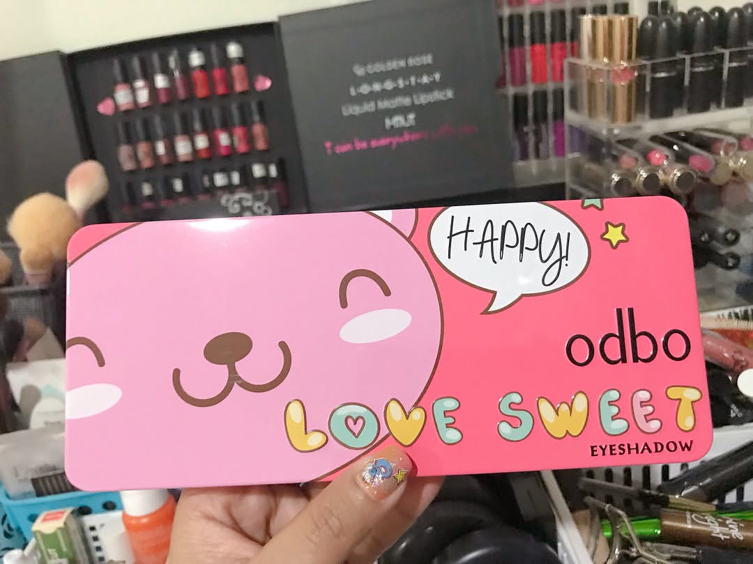 มือถือพาเลตต์ odbo Love Sweet แบบปิดฝาหน้าชั้นวางเครื่องสำอางที่มีลิปสติกเรียงอยู่ฉากหลัง