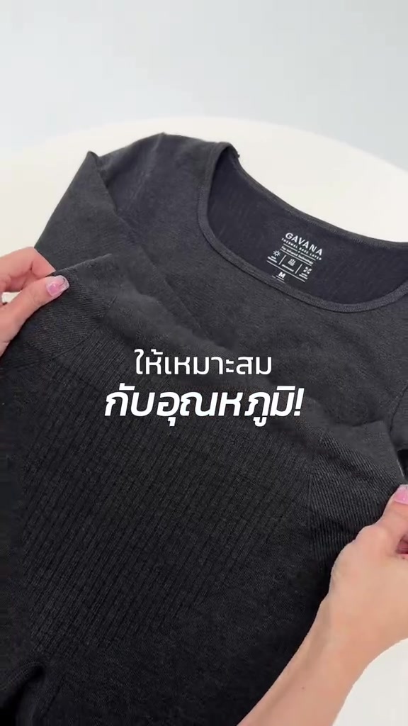มือจับเสื้อลองจอนแขนยาวสีดำให้เห็นเนื้อผ้าริบบริเวณไหล่และคอเสื้อ