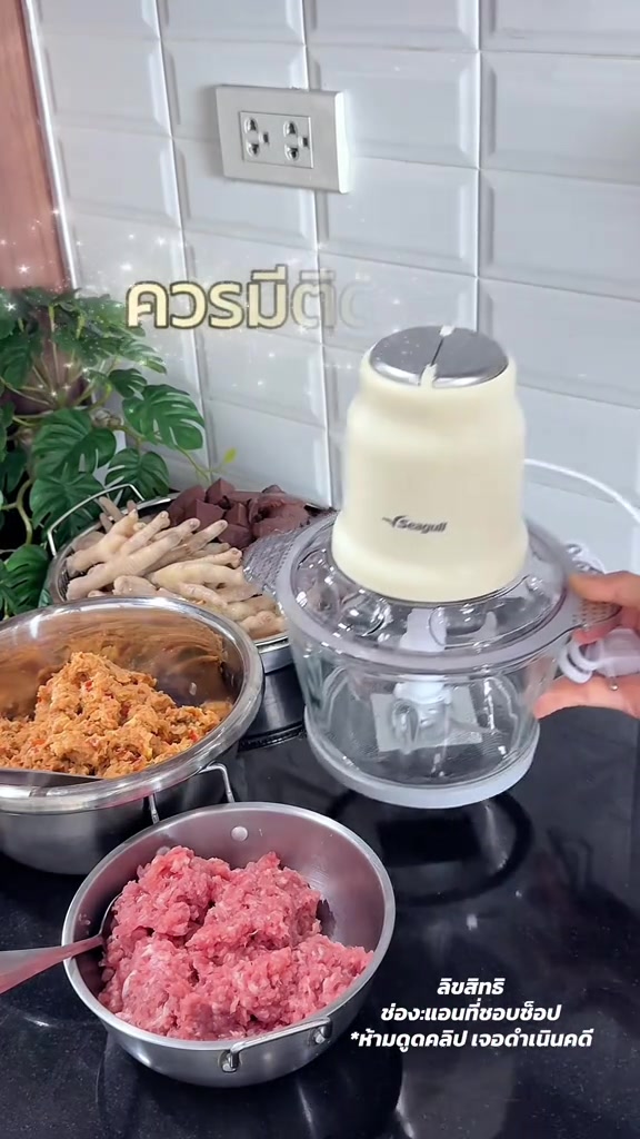 เครื่องบดสับไฟฟ้าสีครีมวางบนเคาน์เตอร์ครัว ข้างกันมีชามสเตนเลสใส่หมูสับสีชมพูละเอียดที่บดเสร็จแล้ว