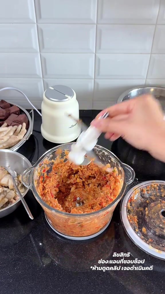 มือยกแกนใบมีดสเตนเลสขึ้นจากโถแก้วที่มีพริกแกงติดอยู่ เพื่อถอดไปล้างแยก