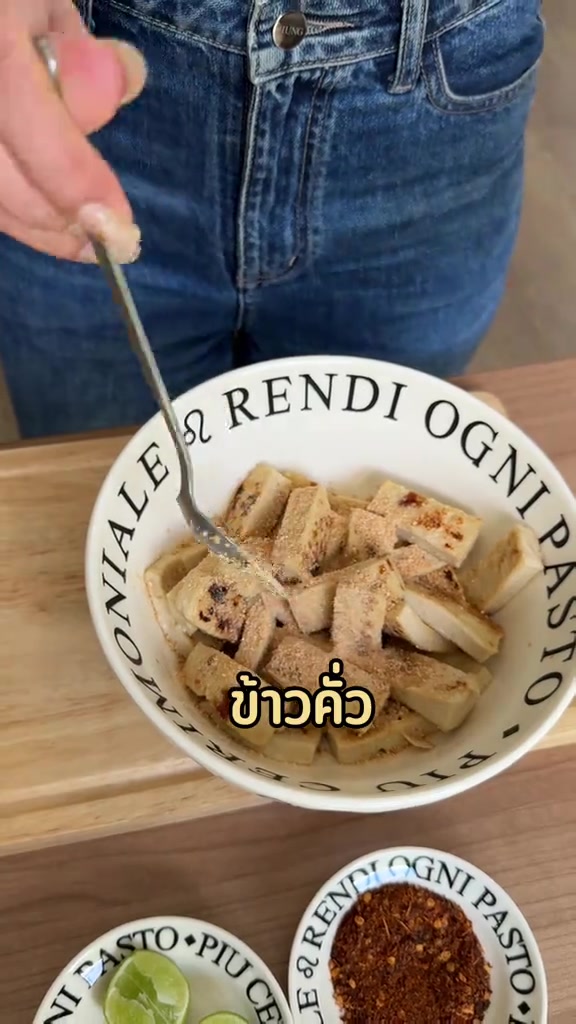มือถือส้อมคลุกเต้าหู้หั่นเต๋าที่โรยข้าวคั่วในชามสีขาว
