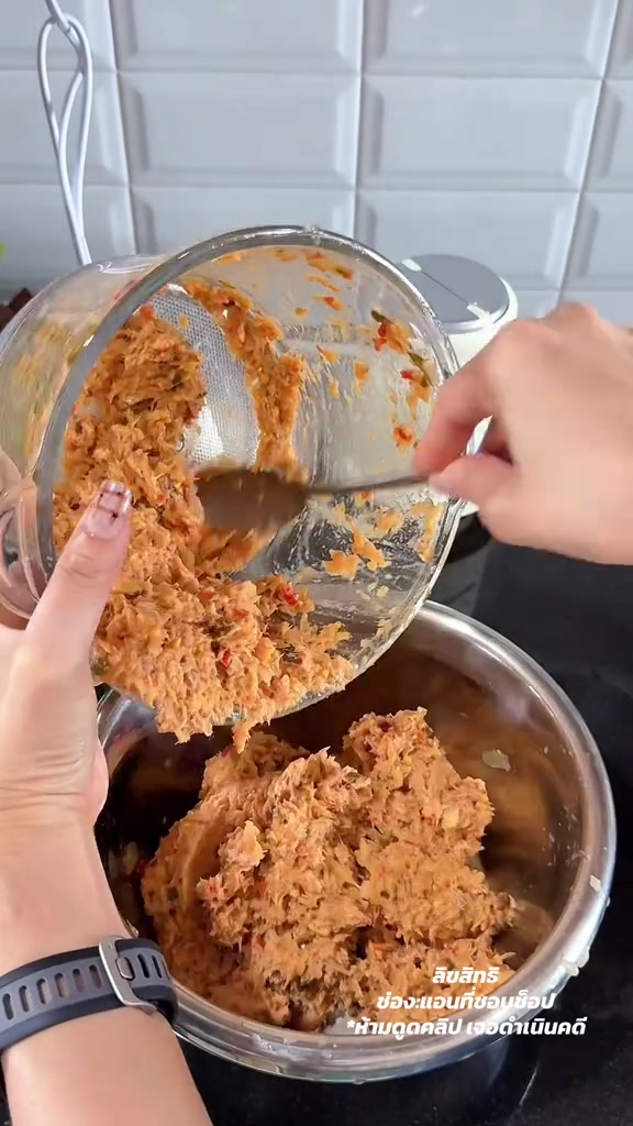 มือใช้ช้อนตักพริกแกงที่ปั่นละเอียดแล้วจากโถแก้วเทใส่ชามสเตนเลส