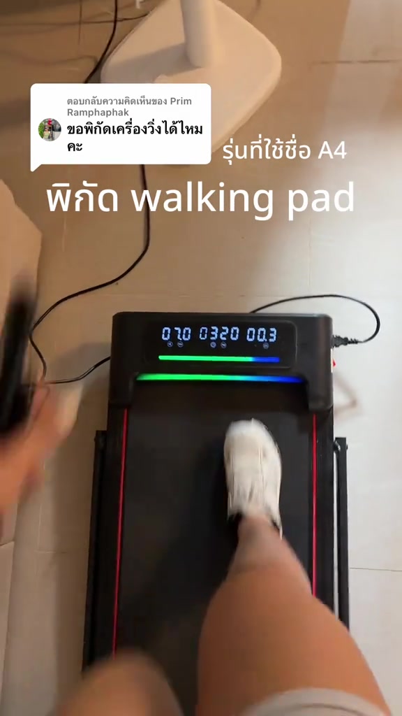 มุมมองจากด้านบนเห็นเท้าสวมรองเท้าขาวก้าวบนสายพาน walking pad สีดำ หน้าจอ LED แสดงตัวเลขความเร็ว เวลา และระยะทาง มือถือรีโมทอยู่ข้างตัว
