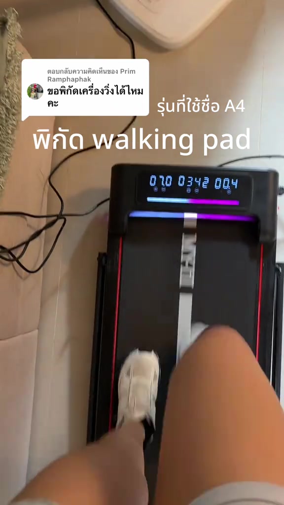 มุมมองจากด้านบนเห็นเท้ากำลังก้าวเดินบน walking pad ที่วางบนพื้นกระเบื้องในบ้าน หน้าจอ LED สว่างแสดงตัวเลขการออกกำลังกาย