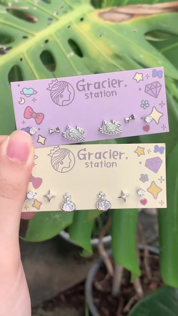 มือถือการ์ดต่างหูสองใบ ใบละหกชิ้น มีทั้งตุ้งติ้งลายคิตตี้ เพชรเรียง และต่างหูคู่จิ๋วบนการ์ดสีพาสเทล