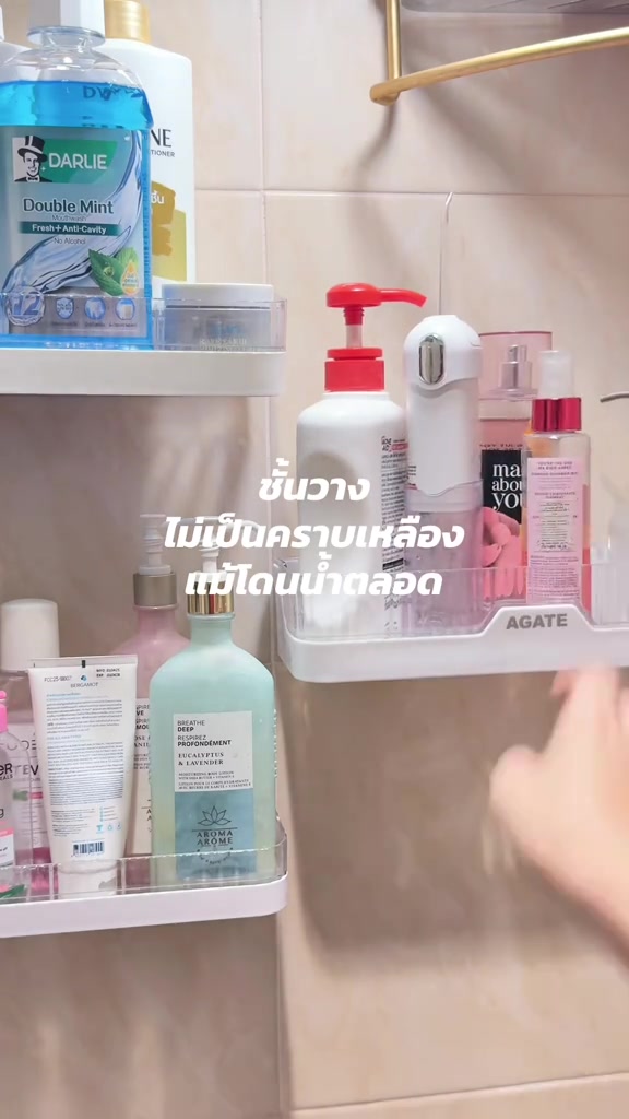 ชั้นวางติดผนังห้องน้ำสองชั้นวางขวดแชมพู โลชั่น และของใช้เรียงเป็นระเบียบ