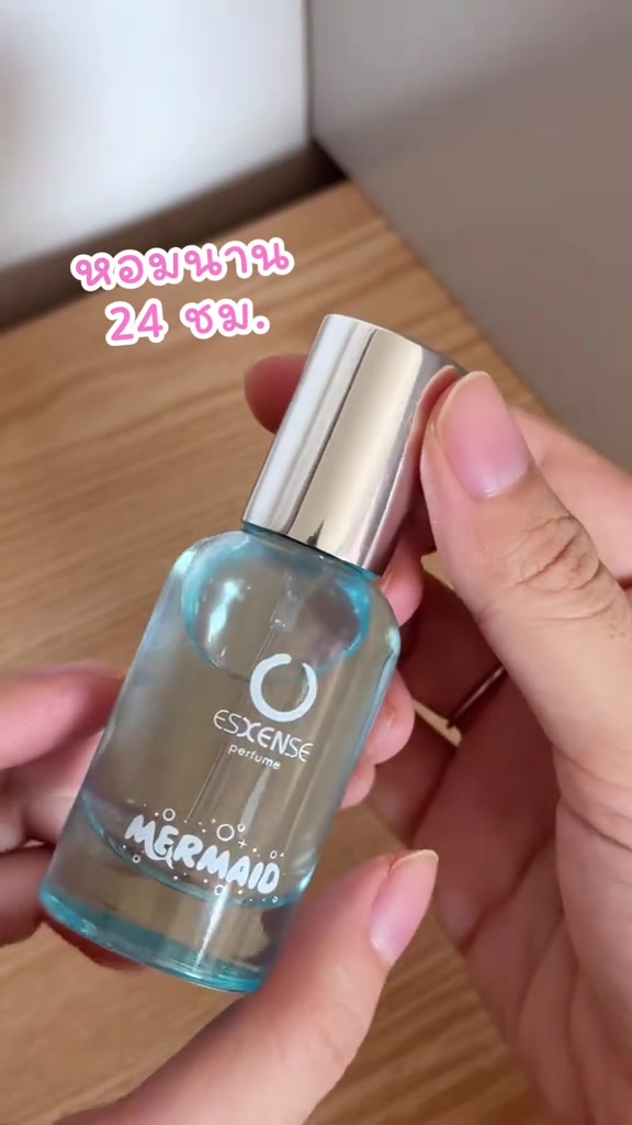ขวดน้ำหอม Esxense กลิ่น Mermaid ขวดแก้วสีฟ้าฝาเงินถือบนโต๊ะไม้
