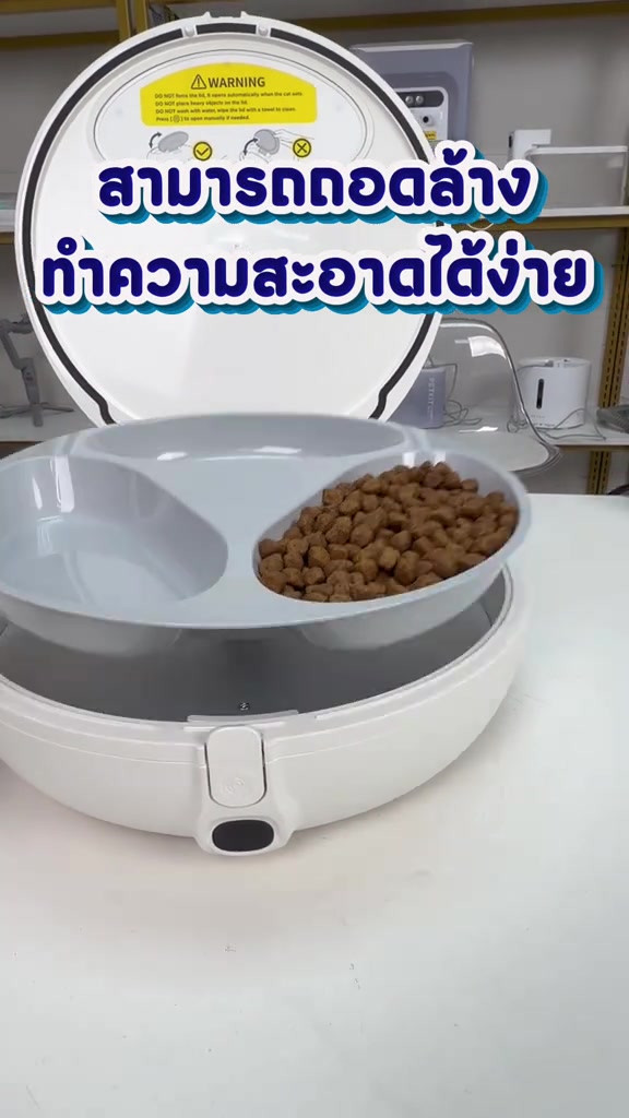 ถาดสามช่องถูกยกออกจากตัวเครื่องให้อาหารอัตโนมัติเพื่อเตรียมล้าง มีอาหารเม็ดอยู่ในหนึ่งช่อง