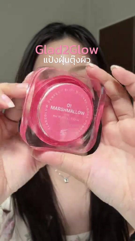 มือสองข้างถือตลับแป้งฝุ่นแกลดทูโกลว์ฝาชมพู เห็นป้ายใต้ตลับเฉด 01 มาร์ชแมลโลว์