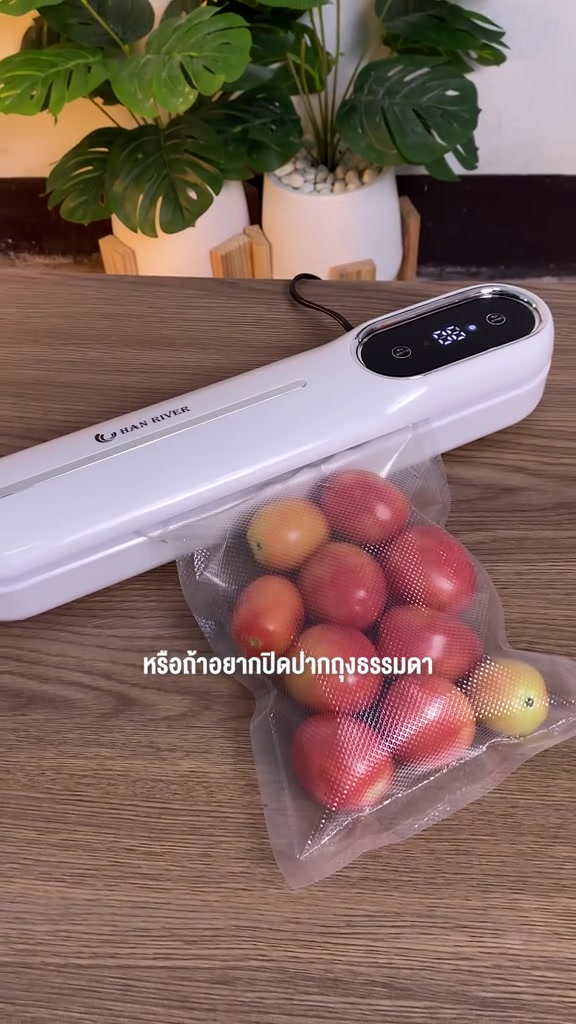 เครื่องซีลสูญญากาศสีขาววางเฉียงบนโต๊ะ ถุงลายนูนใส่มะเขือเทศถูกดูดอากาศจนแนบ
