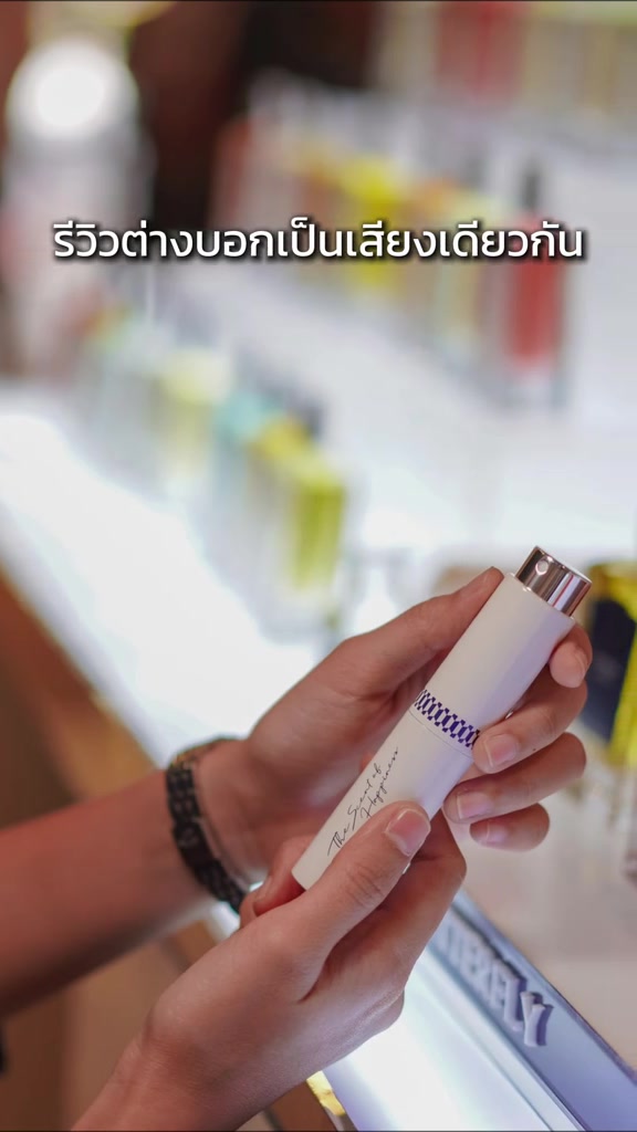 มือถือขวดน้ำหอมtravel size สีขาวของ Butterfly หน้าชั้นวางน้ำหอมในร้าน
