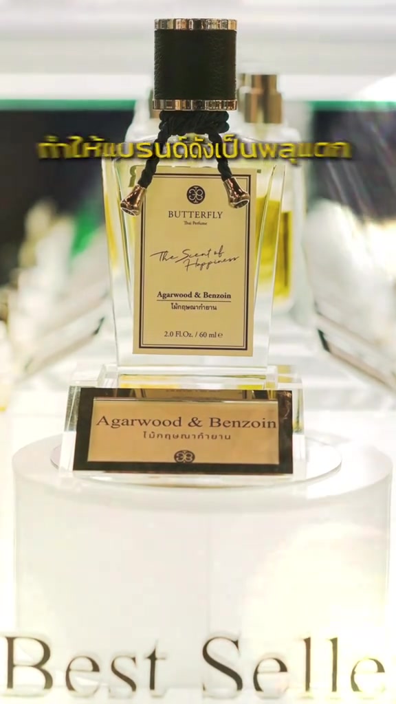 ขวดน้ำหอม Butterfly Thai Perfume กลิ่น Agarwood & Benzoin ขนาด 60 ml ตั้งบนแท่นโชว์สีขาว พร้อมป้ายทองระบุชื่อกลิ่น