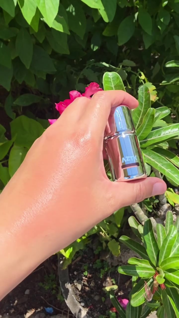 มือถือขวดลิควิดบลัชเอแซดทีเคตัวขวดสีเงินพื้นหลังใบไม้สีเขียว
