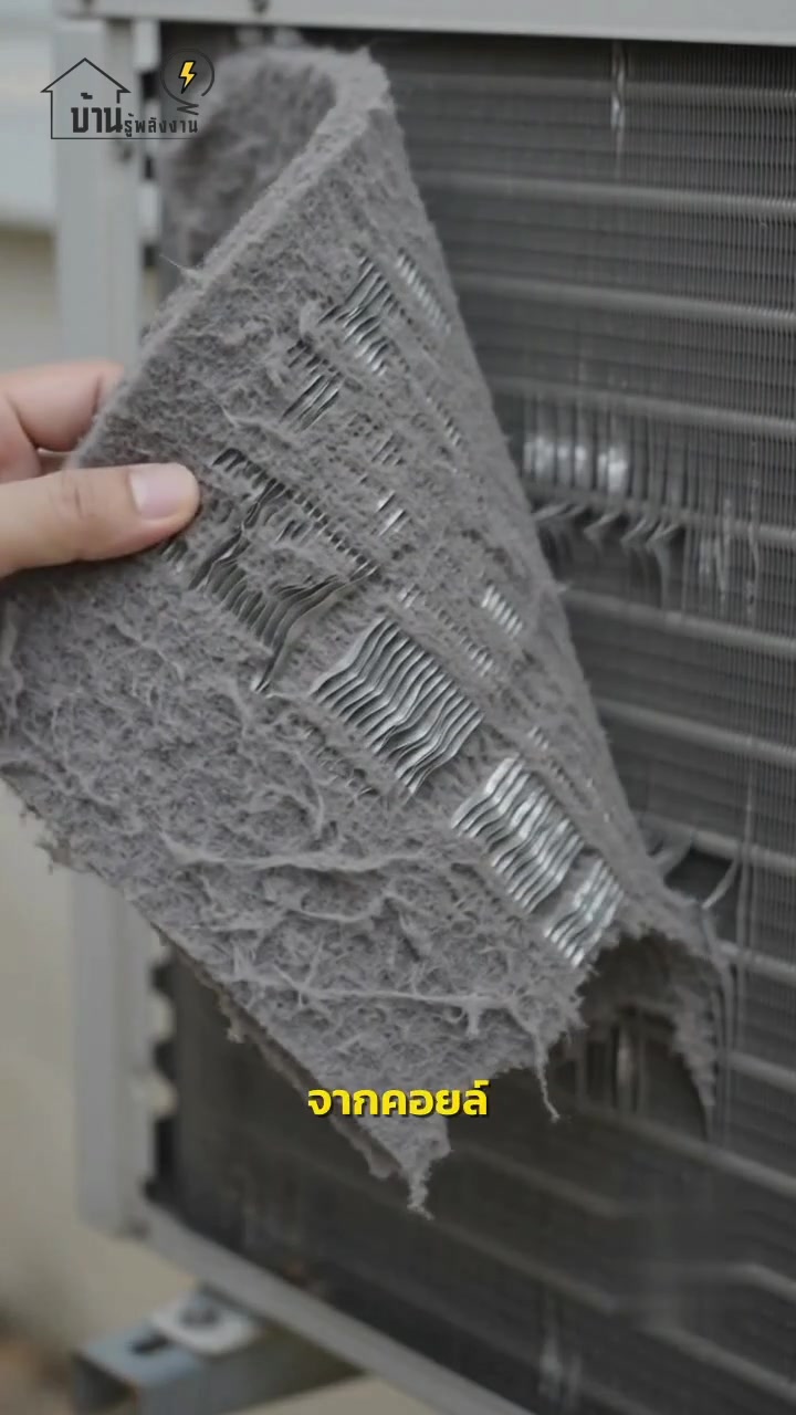มือดึงแผ่นฝุ่นหนาออกจากแผงคอยล์ร้อนของแอร์ เห็นฝุ่นเกาะเป็นแผ่นเทา