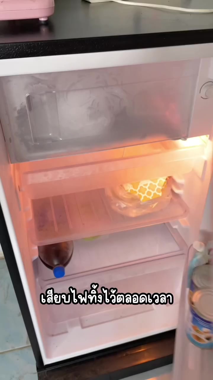 ตู้เย็นเล็กในห้องเช่าเปิดประตูเห็นช่องแช่แข็งและของด้านใน
