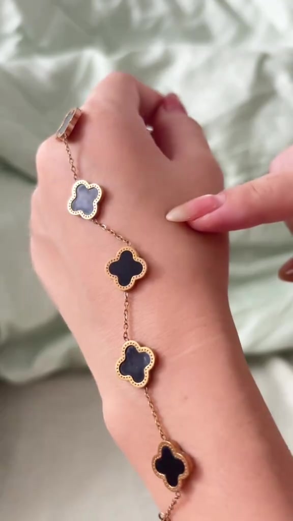 สร้อยข้อมือโซ่สีทองกุหลาบประดับใบโคลเวอร์สีดำสี่ใบเรียงบนหลังมือ