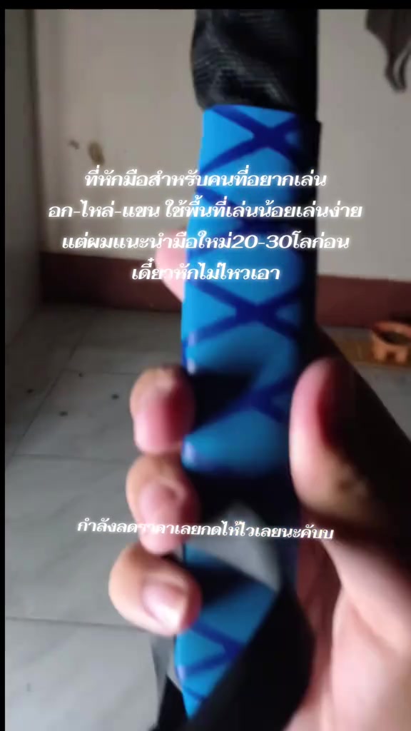 มือกำด้ามโฟมสีน้ำเงินของสปริงมือหักแบบใกล้ชิด เห็นสายรัดข้อมือสีดำห้อยอยู่
