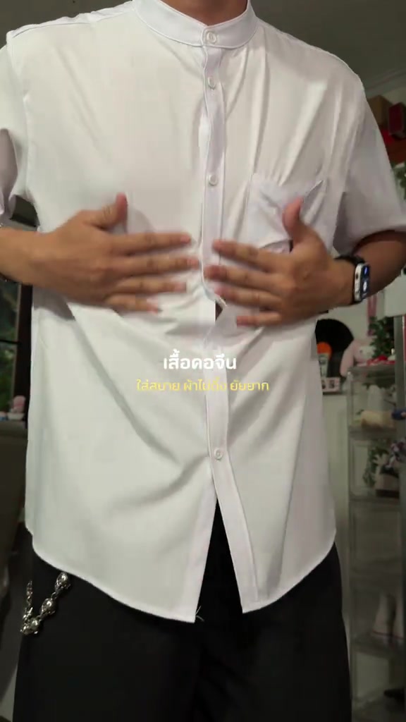 ภาพใกล้ของเสื้อคอจีนสีขาวขณะสวม เห็นแถวกระดุมสีขาวและกระเป๋าอก ภาพครอปไม่แสดงใบหน้า