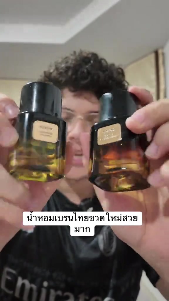 มือชูขวดน้ำหอม BOROM ทรงสี่เหลี่ยมสีอำพันขวดใหม่สองขวด ฝาดำสลักชื่อแบรนด์และป้ายชื่อกลิ่นสีครีมด้านหน้า