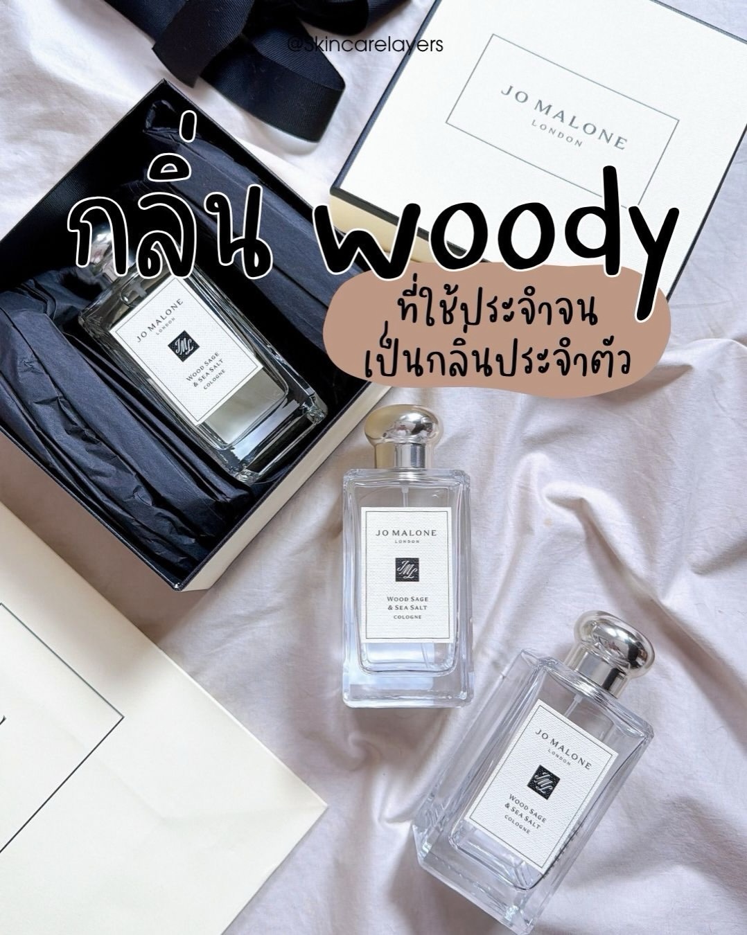 ขวด Jo Malone Wood Sage & Sea Salt Cologne วางบนผ้าสีขาวข้างกล่องสีดำและฝากล่องของแบรนด์