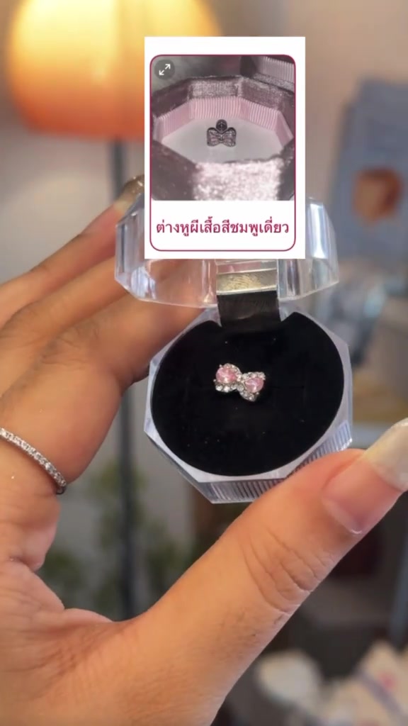 มือถือตลับคริสตัลฝาเปิดใส่ต่างหูโบว์เพชรสี่ชมพู บนภาพมีการ์ดตัวเลือกสินค้าจิวหูจากร้าน