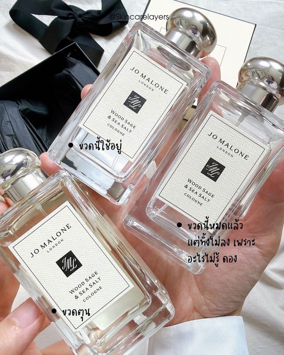 ขวด Jo Malone Wood Sage & Sea Salt สามขวดถือรวมในมือเดียว มีขวดที่พร่องแล้วและขวดใหม่