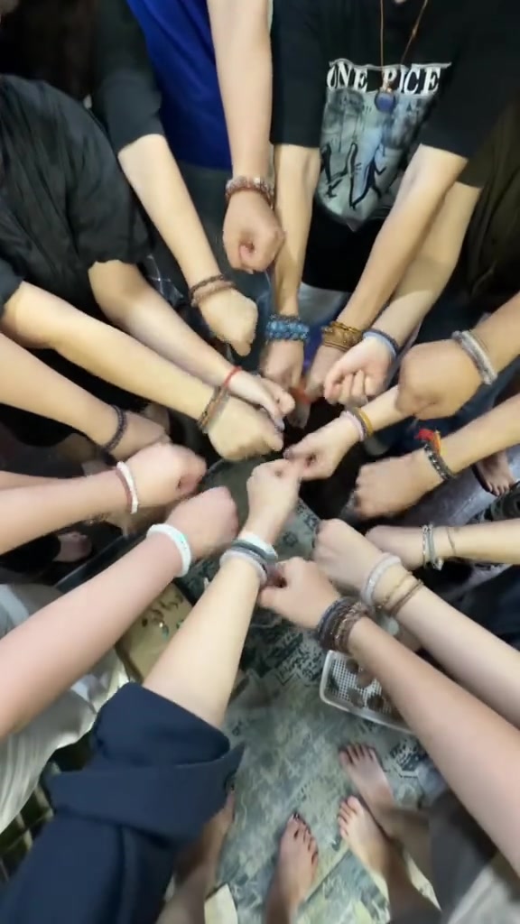 ข้อมือของคนกลุ่มหนึ่ง围วงกลม แต่ละคนใส่กำไลลูกปัดหินคนละสีคนละแบบ