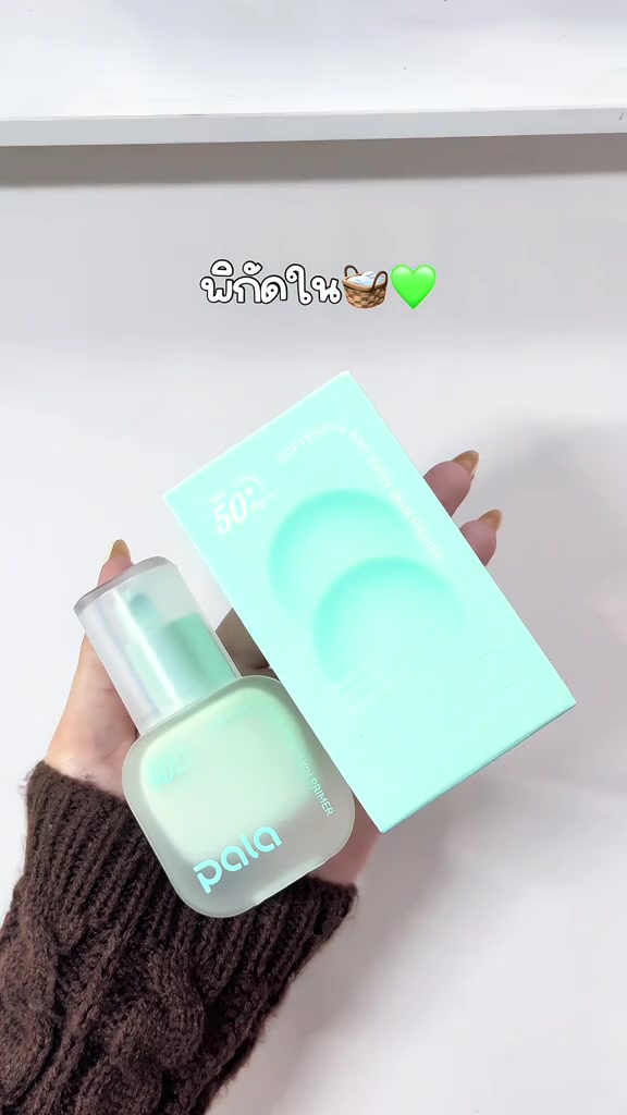 มือถือขวดไพรเมอร์พาลาฝาปั๊มสีเขียวมินต์คู่กับกล่องสีเดียวกันบนพื้นขาว