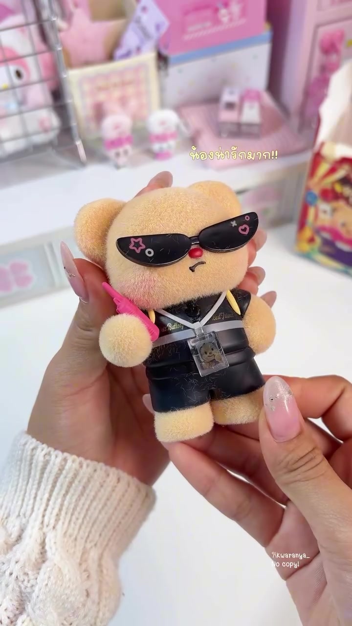 ฟิกเกอร์หมีเนยตัวฟล็อคแบบแบรี่คูลใส่แว่นกันแดดดำและคล้องบัตรพนักงานถืออยู่บนมือ