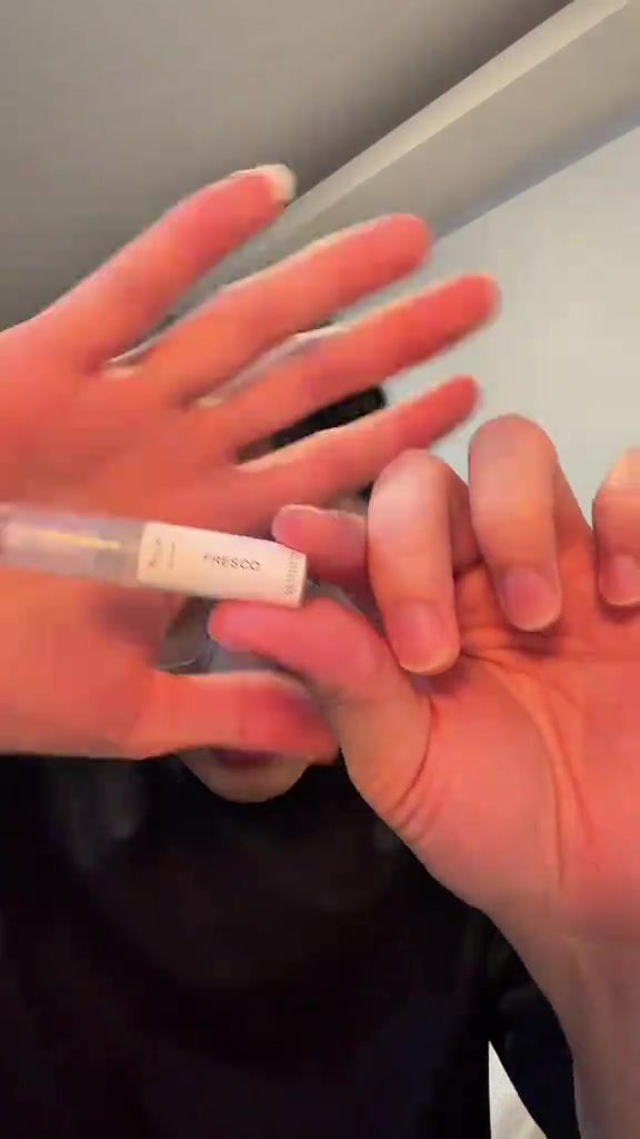 มือถือขวดน้ำหอมขนาดเล็กป้ายชื่อ Fresco ของ eau.dinary ระยะใกล้ เห็นป้ายขาวและน้ำหอมใสในขวด