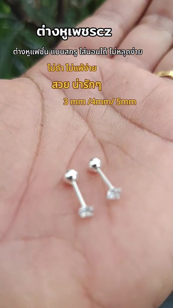 ฝ่ามือวางต่างหูเพชรซีแซดแบบแป้นเกลียวสองเม็ด เห็นปลายก้านเป็นลูกกลมสำหรับหมุนล็อกชัด