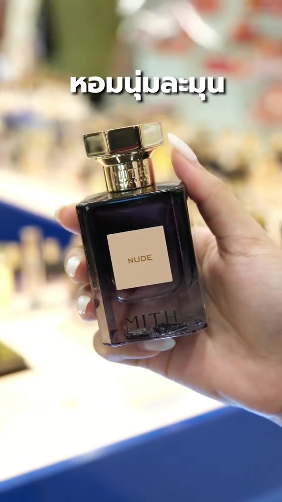 มือถือขวดน้ำหอม MITH NUDE ตัวขวดสีเทาไล่เฉด ฉลากสีเบจอ่านว่า NUDE