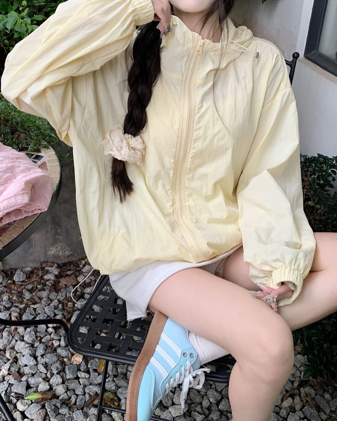 คนนั่งสวมเสื้อกันแดดมีฮู้ดสีเหลืองอ่อนตั้งแต่คอลงมาเห็นยางรัดปลายแขนและซิปหน้าชัด