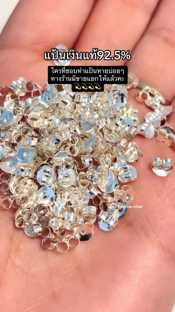 แป้นต่างหูเงินแท้ 925 จำนวนมากกองบนฝ่ามือ เห็นจานแบนและปีกหนีบชัดทุกชิ้น