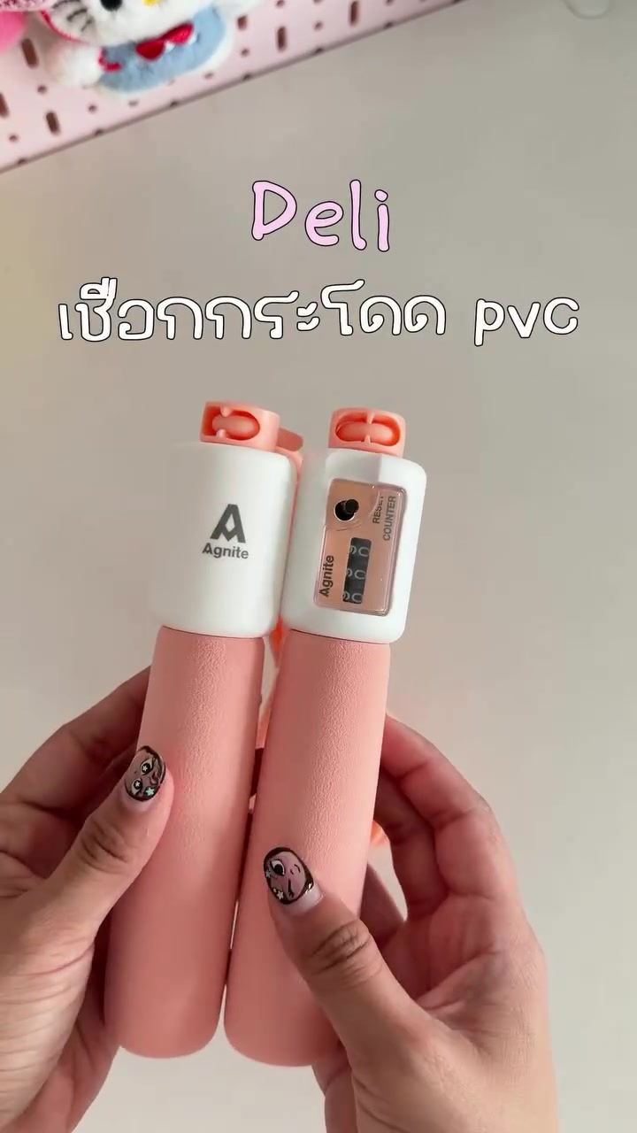 มือถือด้ามเชือกกระโดดสีชมพูขาวสองด้าม ด้ามขวามีหน้าต่างตัวนับรอบและปุ่มกดบนพื้นหลังสีอ่อน