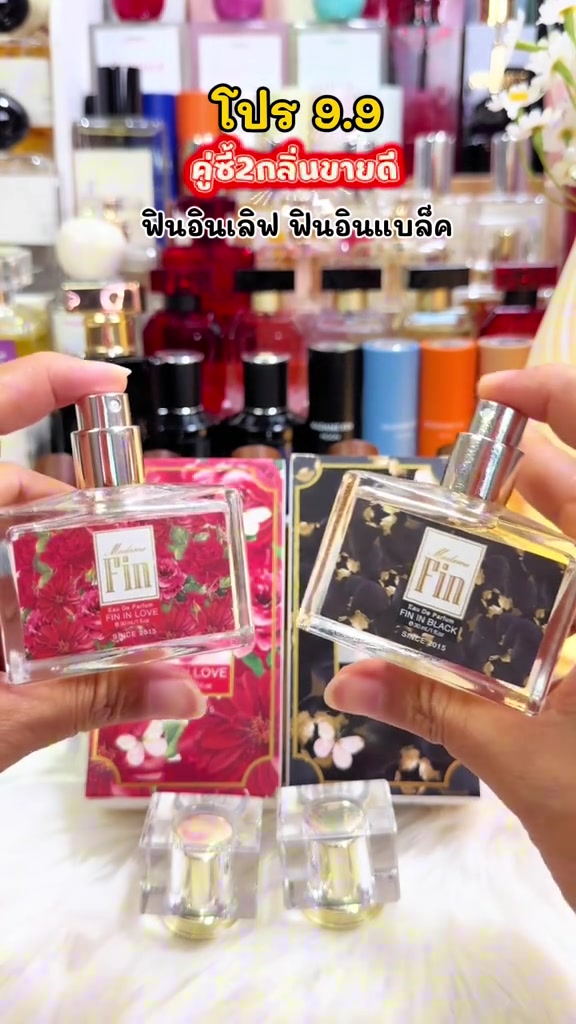 มือถือขวดน้ำหอม Madame Fin Fin in Love ฉลากกุหลาบแดงและ Fin in Black ฉลากดำทองเปิดฝาโชว์หัวสเปรย์ ด้านหลังเป็นกล่องลายดอกไม้และชั้นน้ำหอม