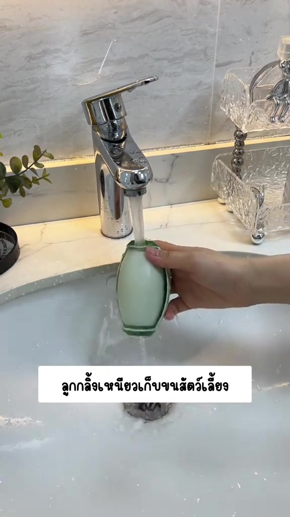 มือถือลูกกลิ้งเหนียวสีเขียวอ่อนล้างใต้ก๊อกน้ำในอ่างล้างหน้าสีขาว