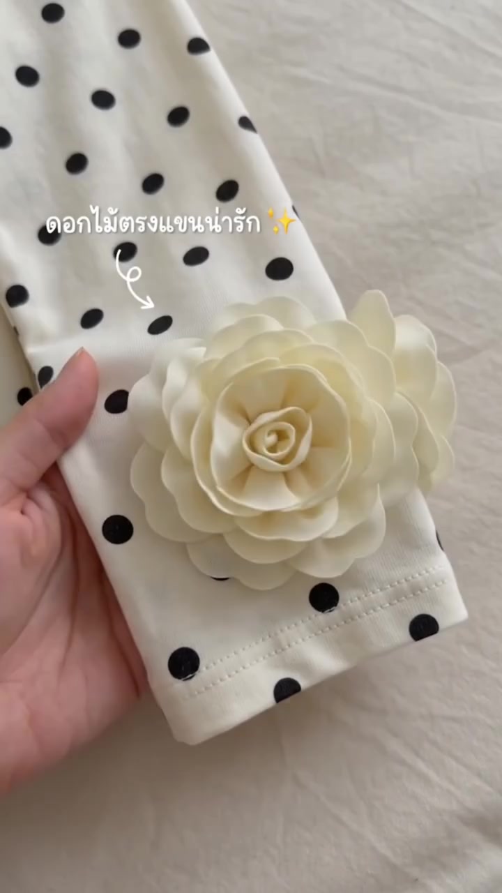 มือจับปลายแขนเสื้อลายจุดพื้นครีมที่แต่งดอกผ้าสีครีมดอกใหญ่ไว้ตรงปลายแขน