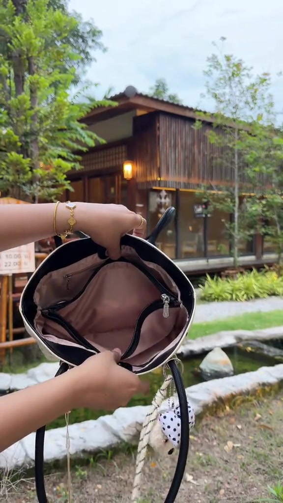 กระเป๋าโท้ทลายจุดสีครีมตัดดำถูกเปิดโชว์ซับในและช่องซิปด้านใน