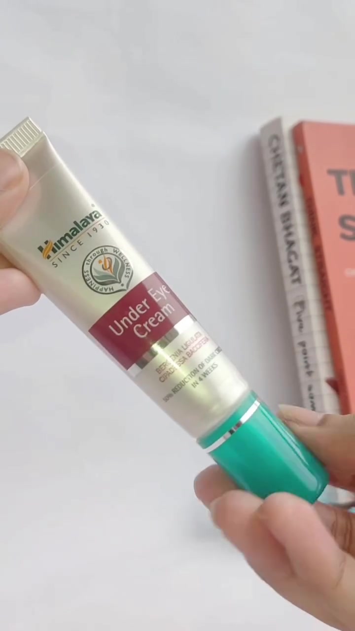 มือถือหลอดหิมาลายา อันเดอร์ อาย ครีม สีครีมฉลาแดงเข้ม ฝาเขียวอมฟ้า บนพื้นหลังสีขาว