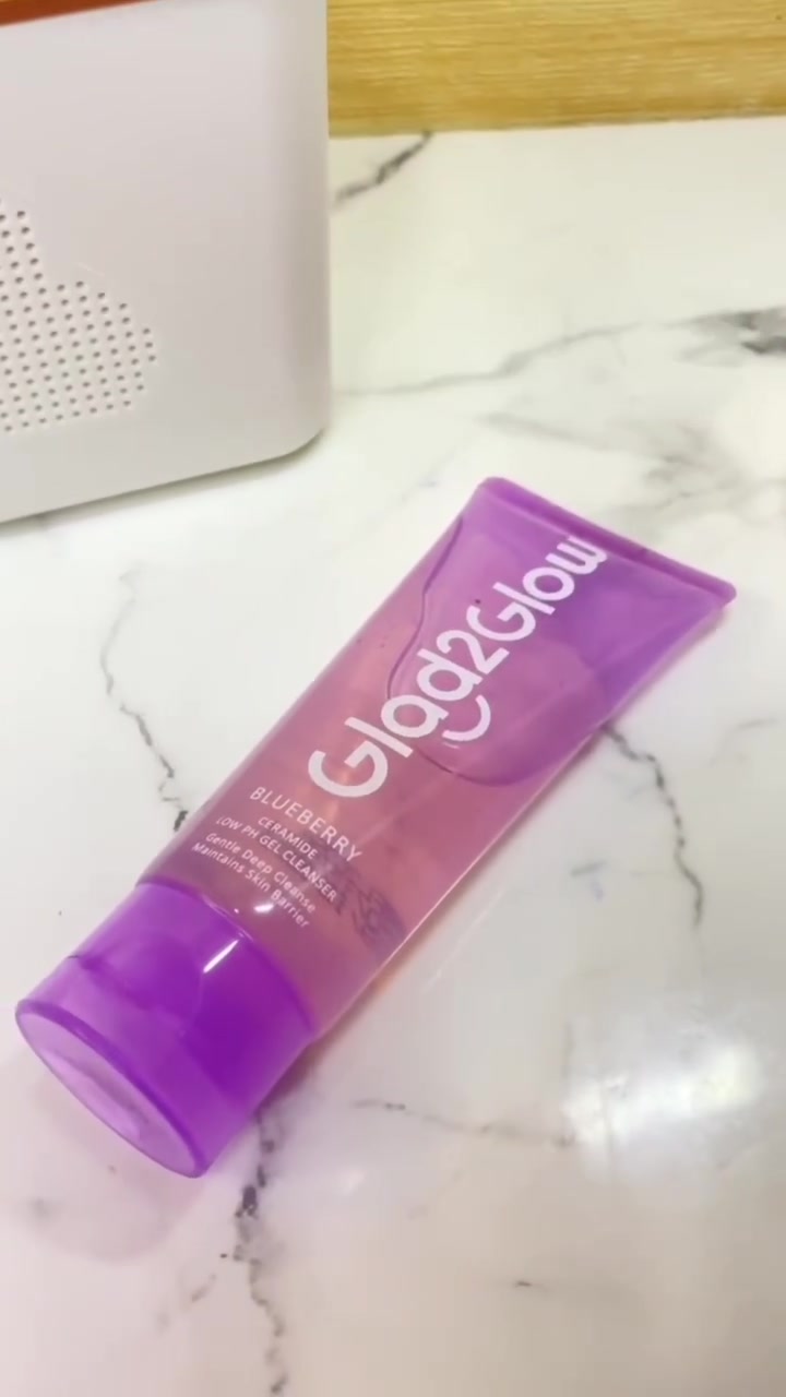 หลอดเจลล้างหน้าแกลดทูโกลว์สูตรบลูเบอร์รีเซราไมด์สีม่วงใสวางบนพื้นลายหินอ่อน