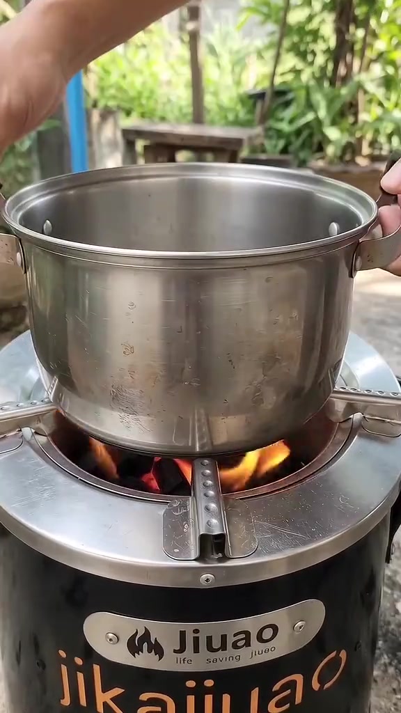 หม้อวางบนเตาถ่านที่มีไฟอยู่ด้านล่างในพื้นที่เปิดโล่ง