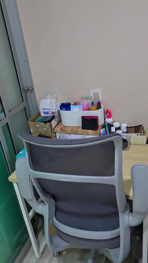 โต๊ะทำงานวางอยู่ข้างบานกั้นกระจกในคอนโดขนาดเล็ก