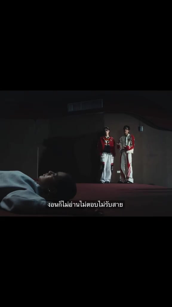 ฉากกว้างในคลิปเพลง มีคนเอนอยู่ด้านหน้าและคนสองคนยืนอยู่ด้านหลัง