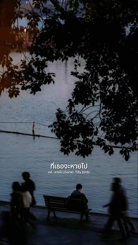 ม้านั่งริมแม่น้ำใต้เงาไม้ มีผู้คนเดินผ่านเป็นเงาและข้อความเพลงซ้อนอยู่ในภาพ