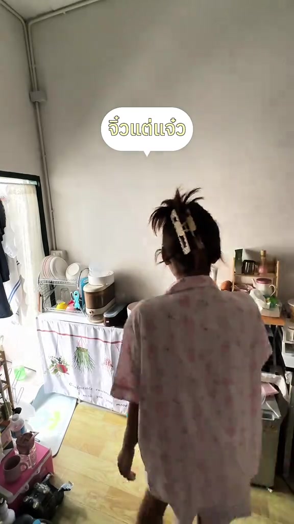 ห้องพักขนาดเล็กมีเตียง โต๊ะทำงาน และคนยืนหันหลังอยู่กลางห้อง